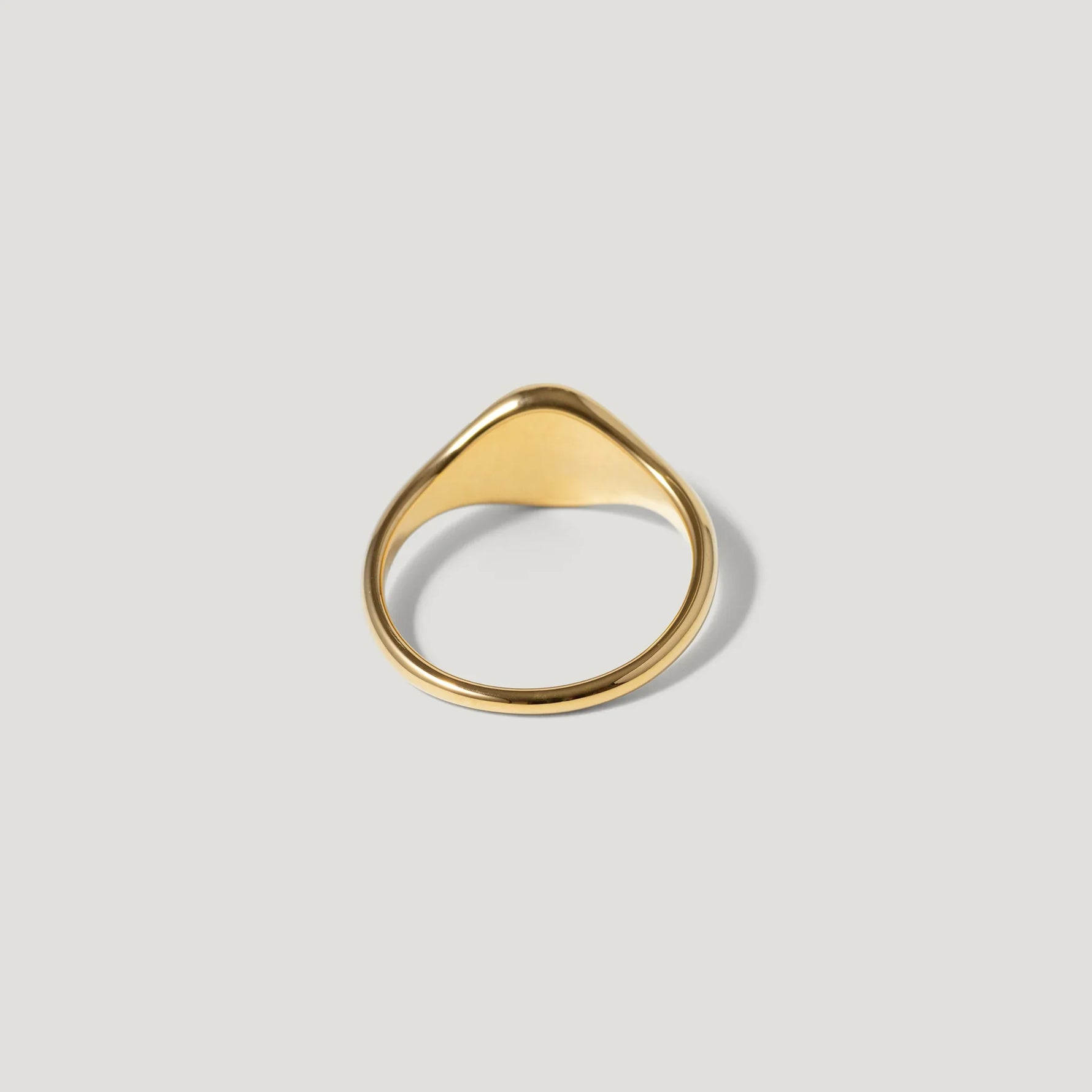 Minimalist gold signet ring on a light background