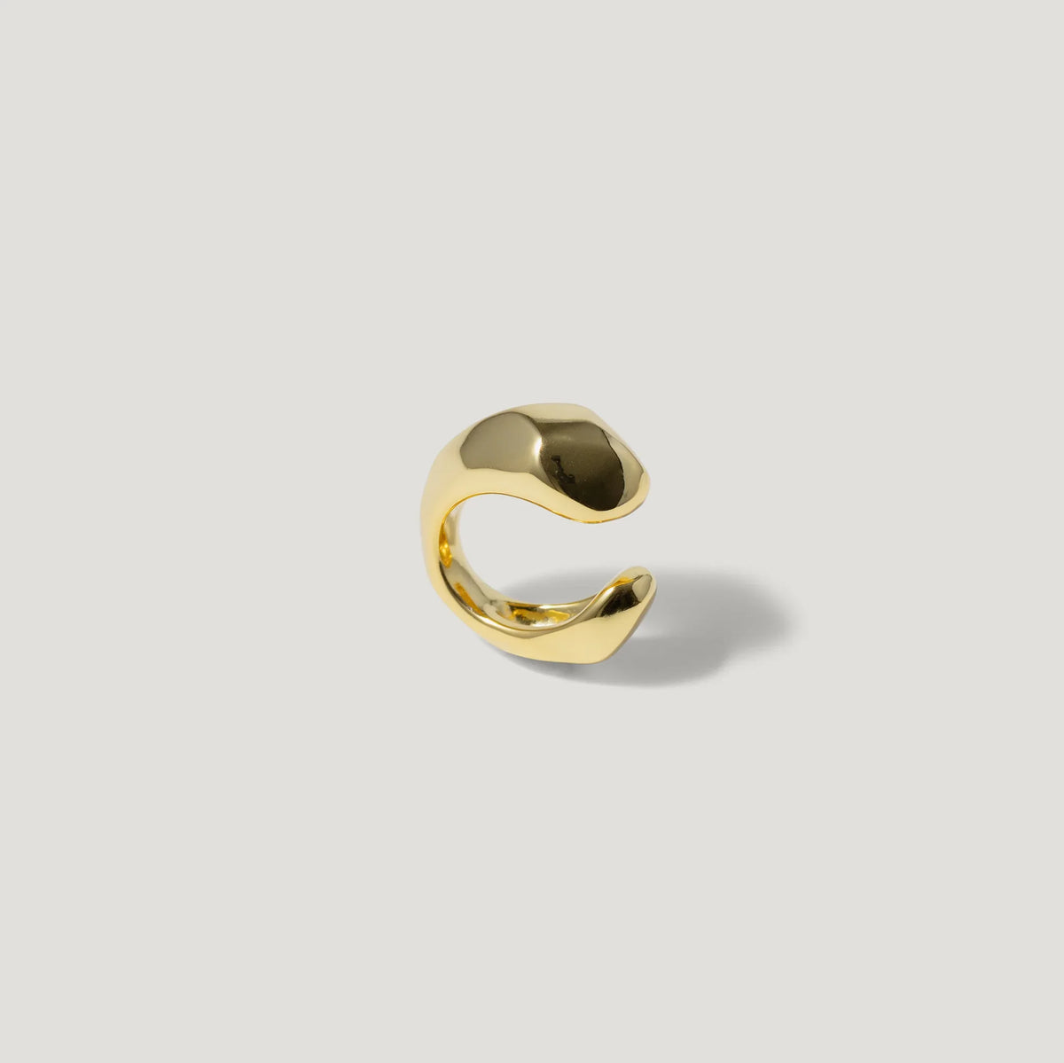 Gold open band ring with modern, sculptural design on a light background