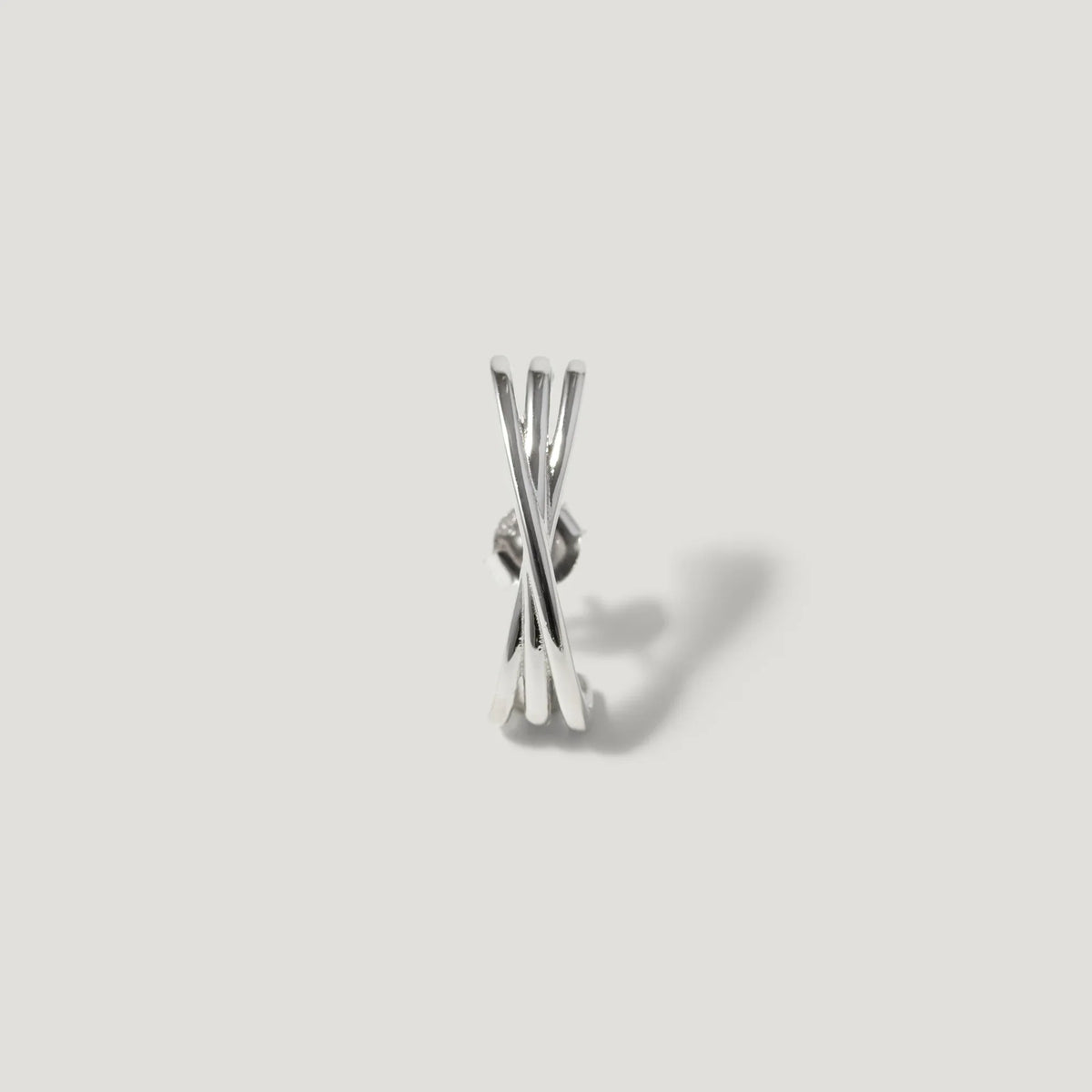 Minimalist silver stud earring with intersecting bars on a light grey background
