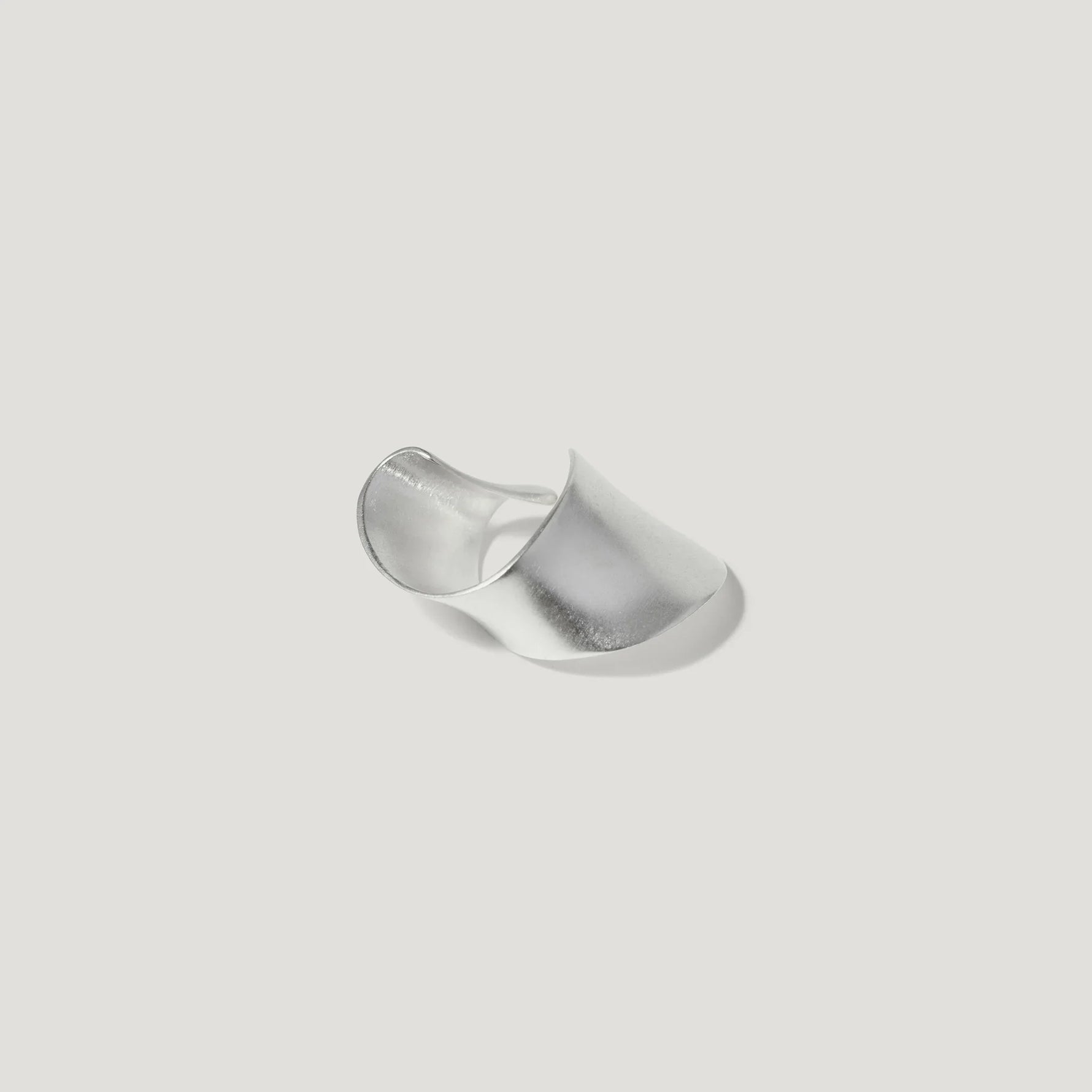 Modern wide sterling silver statement ring with smooth matte finish on white background