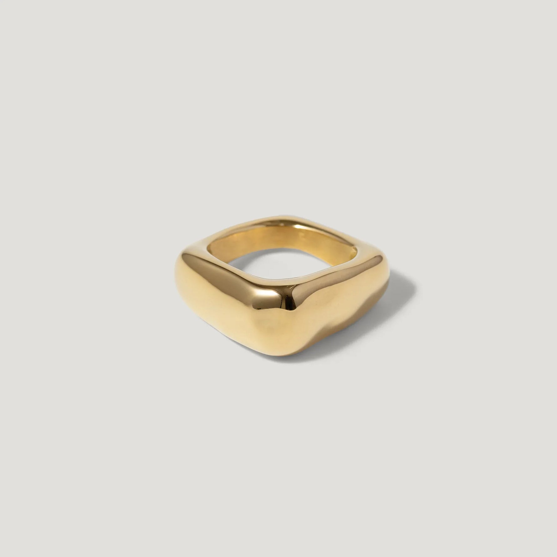 Modern gold square signet ring with smooth, minimalist design on a light background