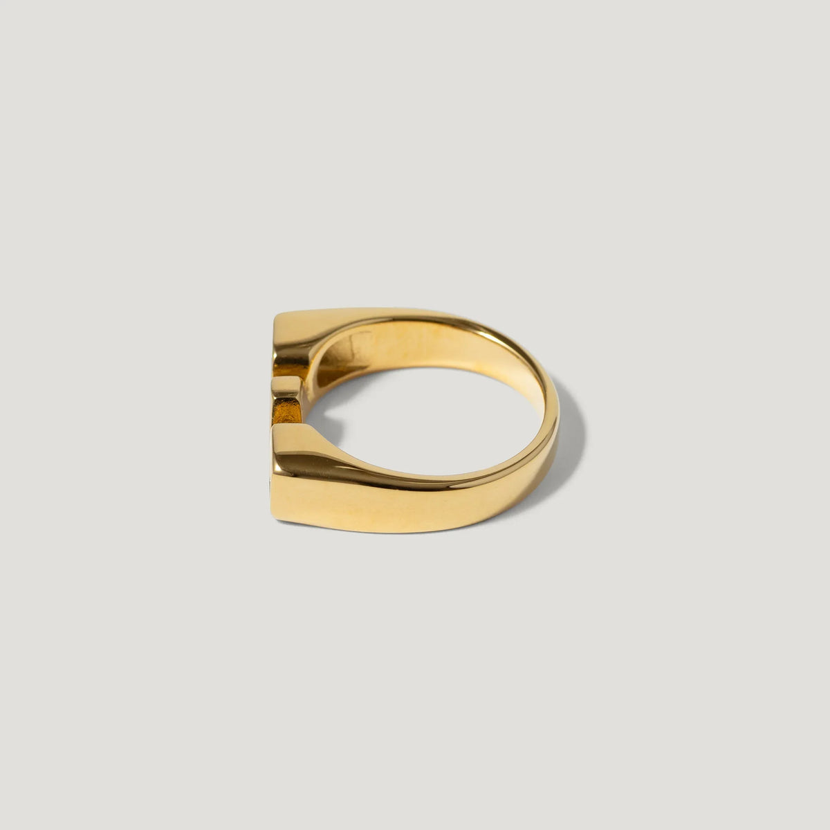 Gold geometric ring with a modern, flat-top design on a plain light background