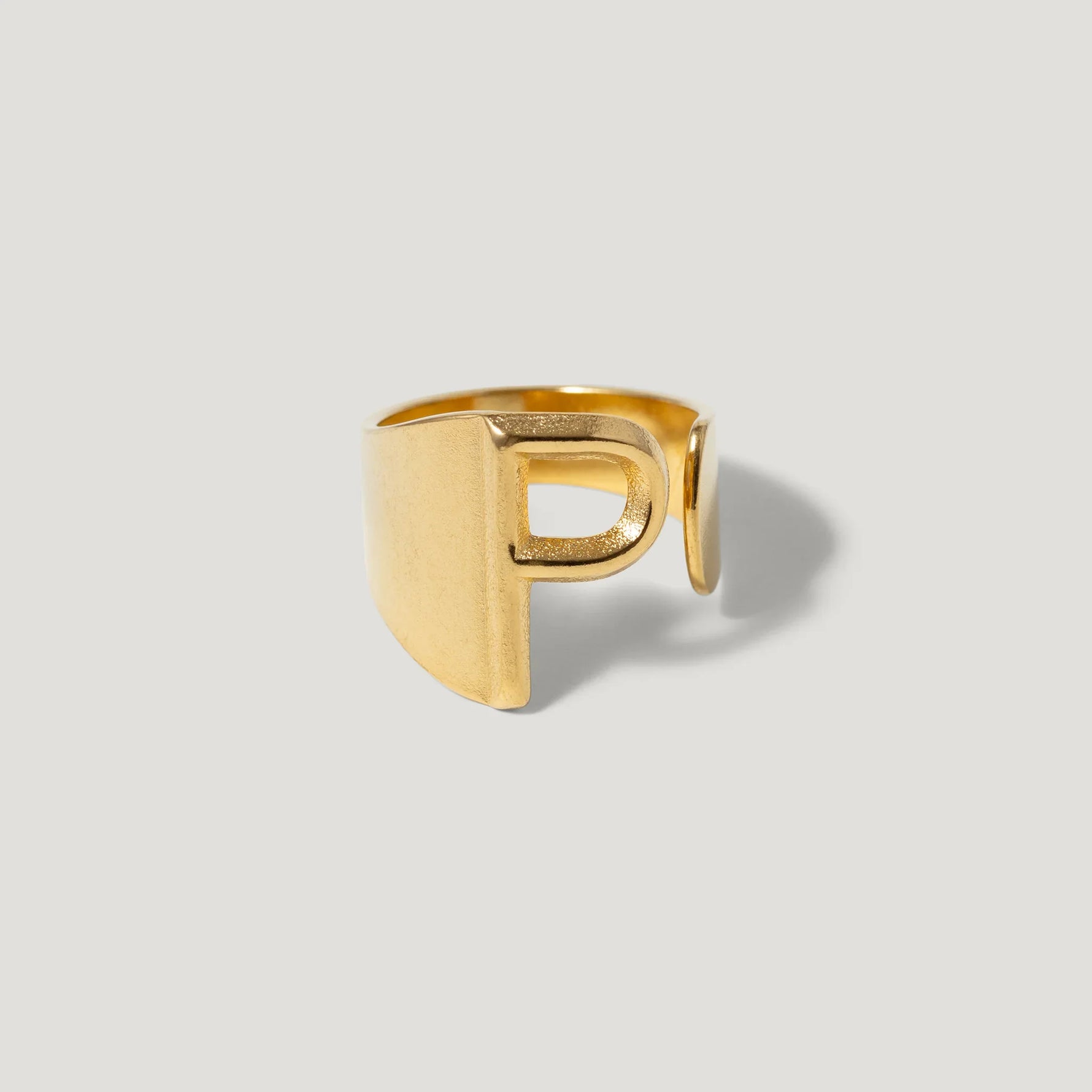 Gold adjustable ring with a bold letter P design on a light background