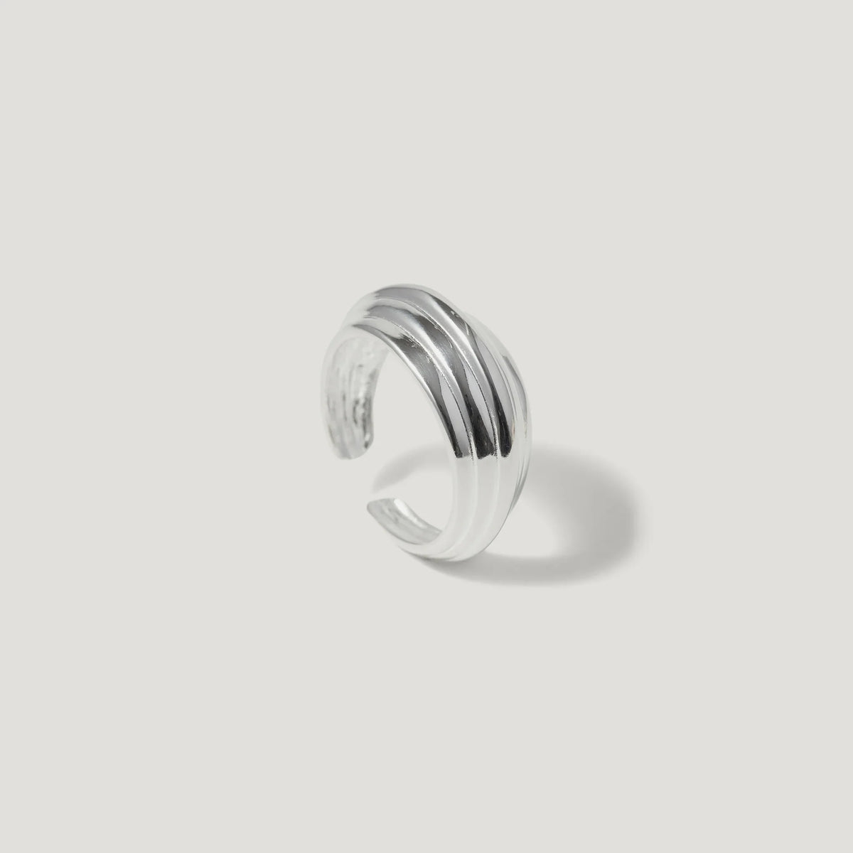 Textured silver ear cuff with grooved design on a plain light background