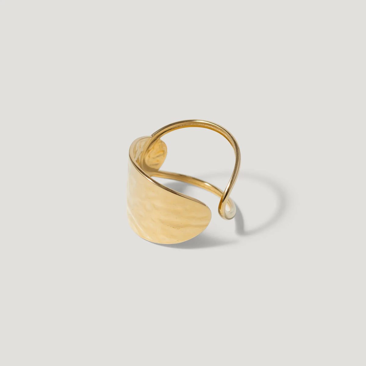 Hammered gold adjustable ring with open band on light background