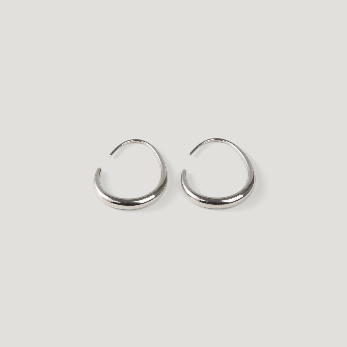 Silver tapered open hoop earrings with thin wire posts, on light background