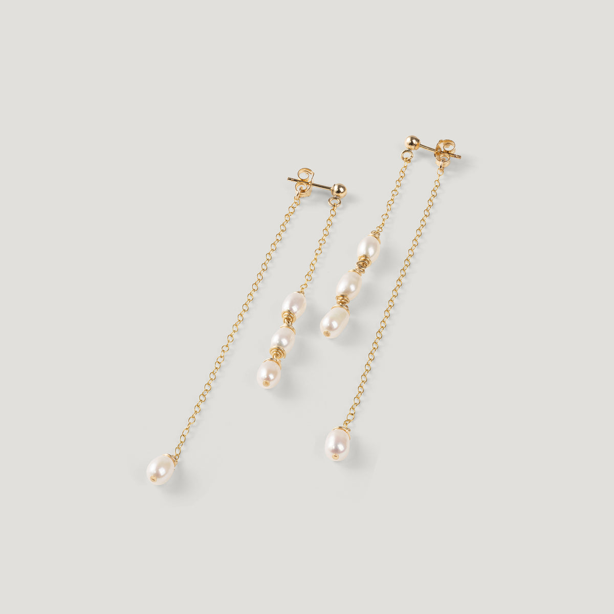 Pair of gold pearl drop earrings with clustered pearls, on light background.