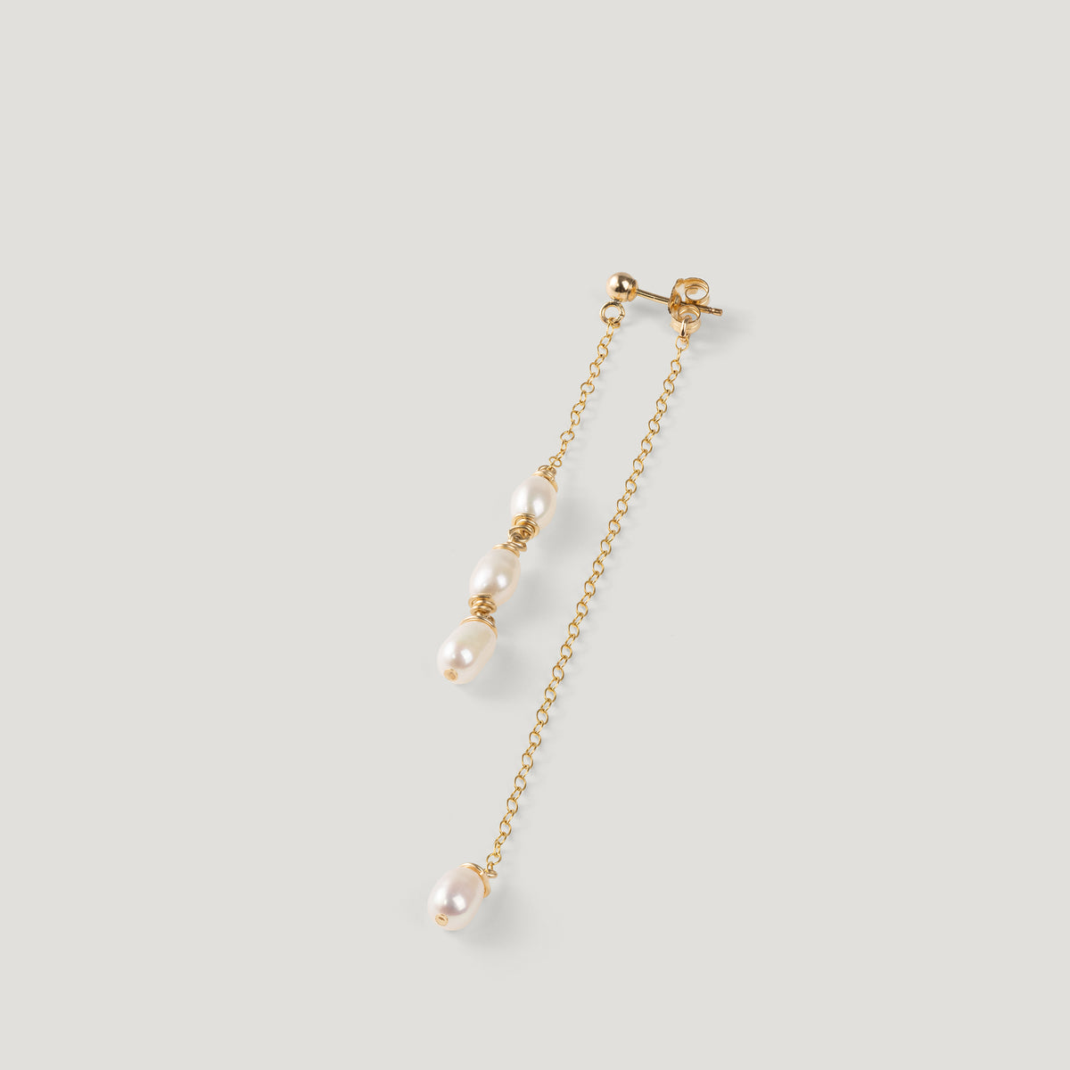 Single gold pearl drop earring laid diagonally, showing clustered pearls and chain.