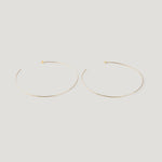 Pair of thin gold hoop earrings, laid flat on light background.