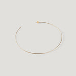 Single gold hoop earring, laid flat and curved on light background.