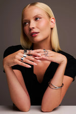 Woman wearing modern silver rings, bracelets, and ear cuff jewelry on hands and ear