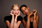 Two women wearing elegant rings, bracelets, and earrings in a studio setting