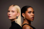 Two women wearing bold, sculptural metal earrings against a neutral background