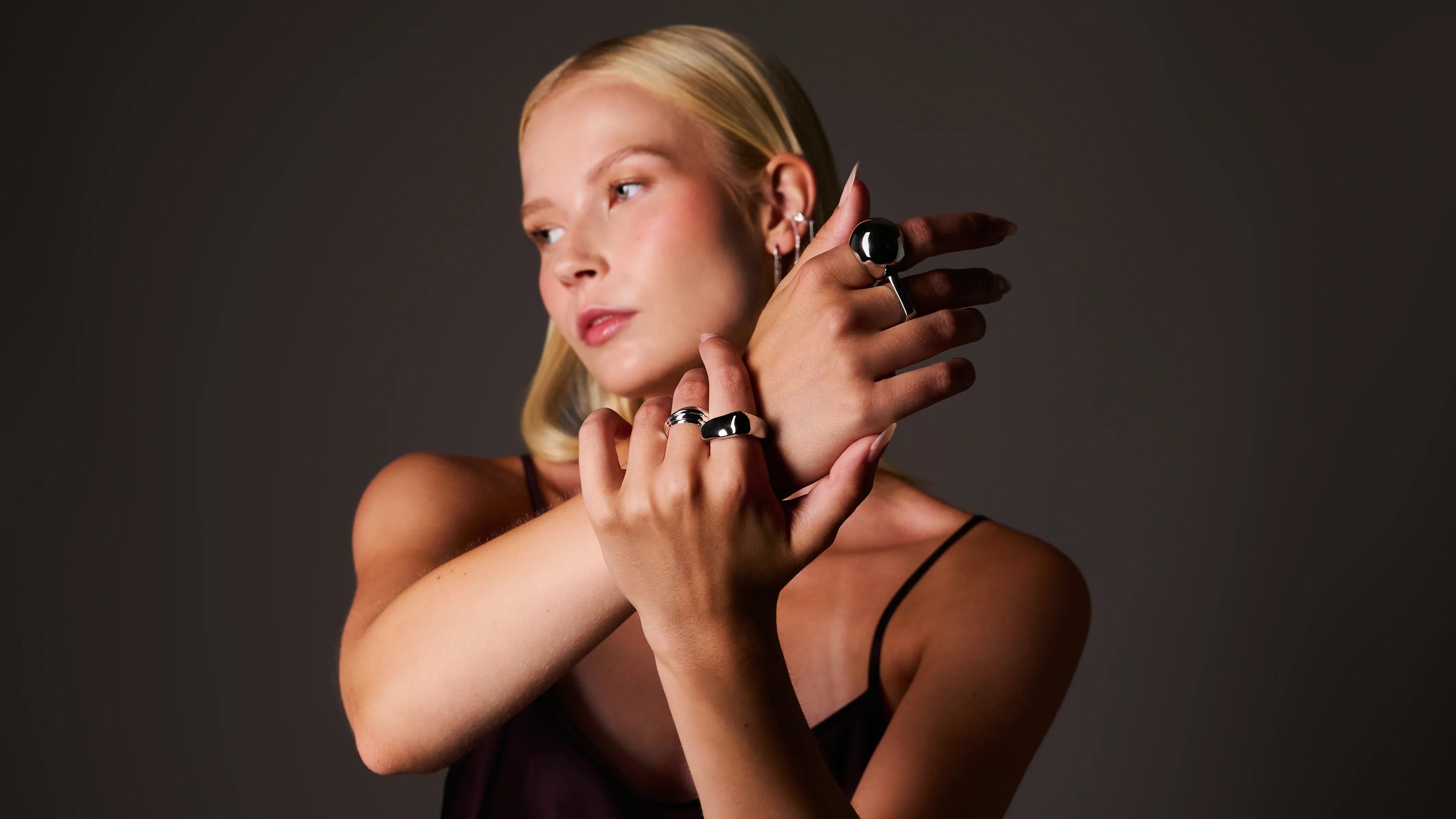 Woman wearing silver statement rings and earrings, minimalist jewellery style