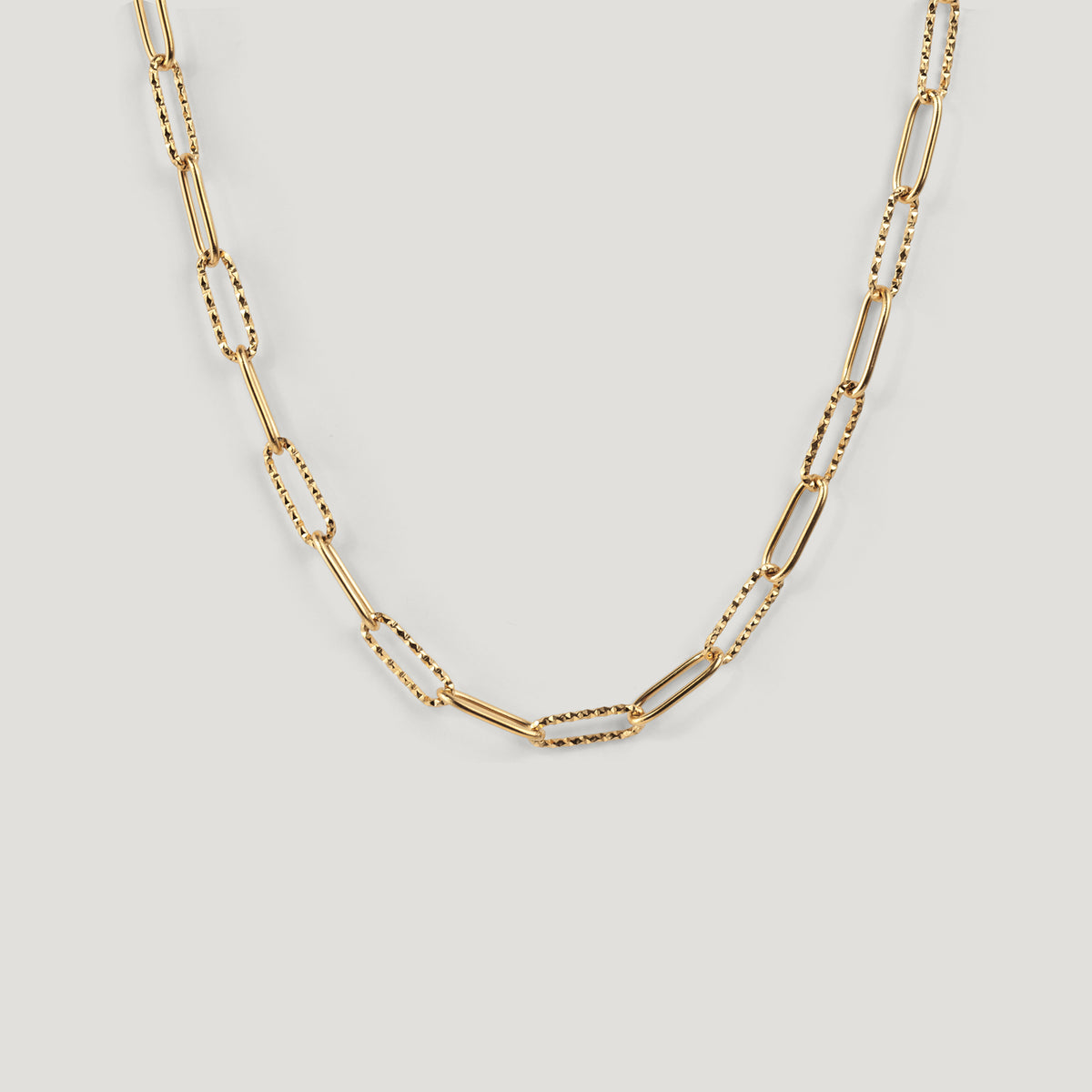 Gold chain necklace with alternating smooth and textured paperclip links, laid flat.