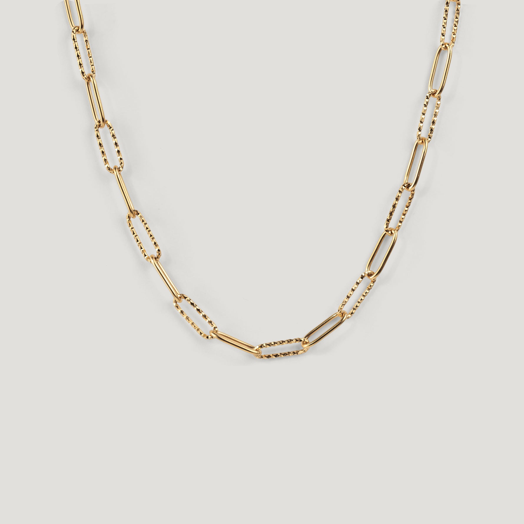 Gold chain necklace with alternating smooth and textured paperclip links, laid flat.