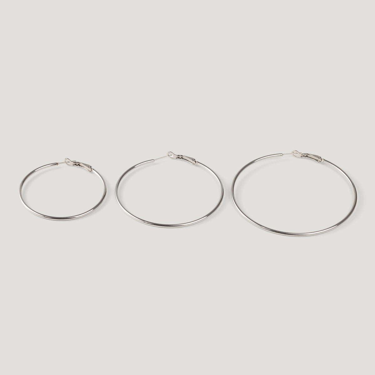Three silver hoop earrings in ascending sizes, thin wire with clasp closures, side by side.