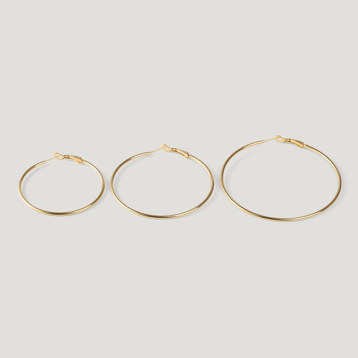 Three gold hoop earrings in ascending sizes, thin wire with clasp closures, side by side.