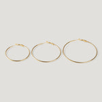 Three gold hoop earrings in ascending sizes, thin wire with clasp closures, side by side.