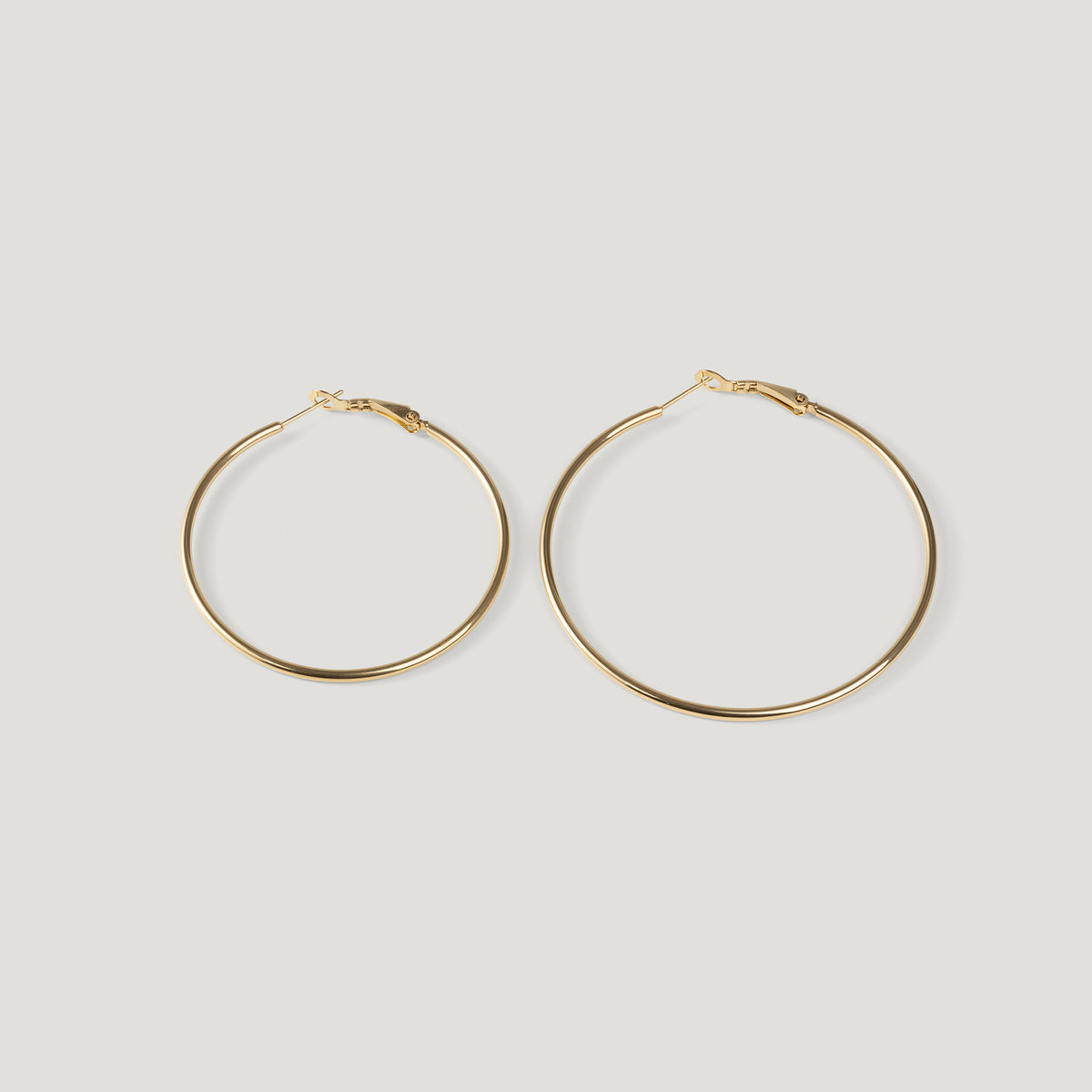 Pair of large gold hoop earrings, thin wire with clasp closures, side by side.