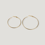 Pair of large gold hoop earrings, thin wire with clasp closures, side by side.