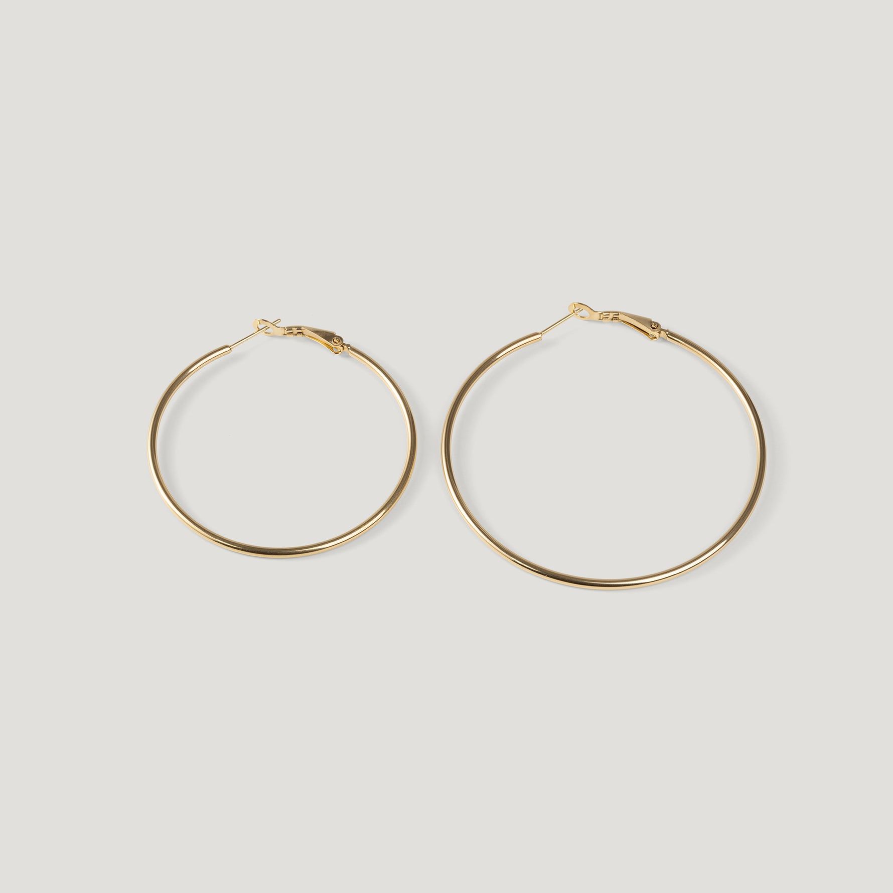 Pair of large gold hoop earrings, thin wire with clasp closures, side by side.
