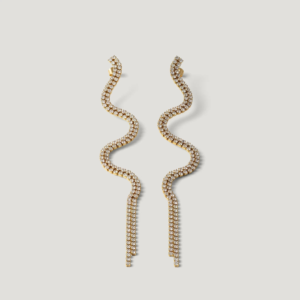 Gold wavy tassel earrings with sparkling crystals on a white background