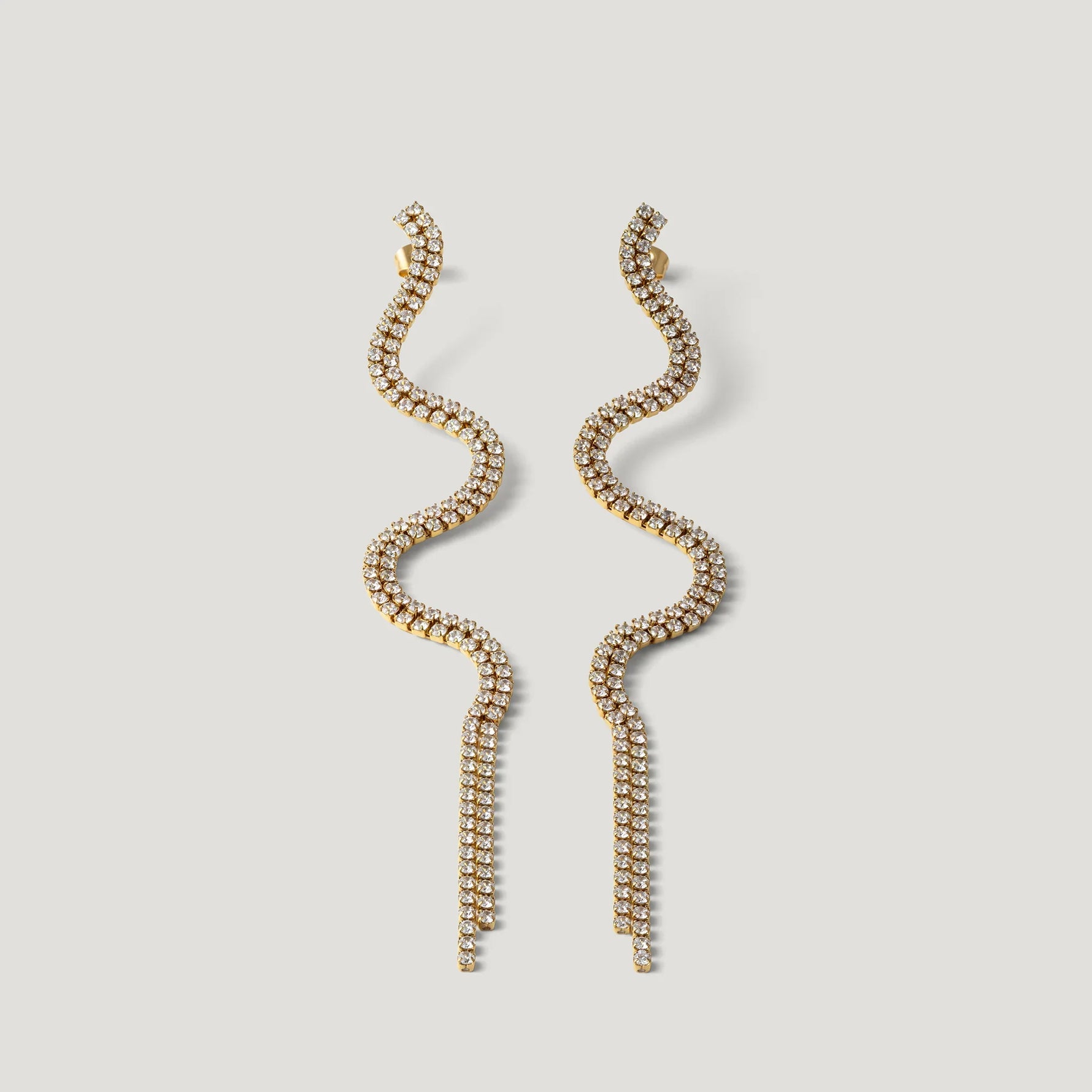 Gold wavy tassel earrings with sparkling crystals on a white background