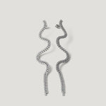 Pair of wavy silver tassel earrings with sparkling crystals on a light background