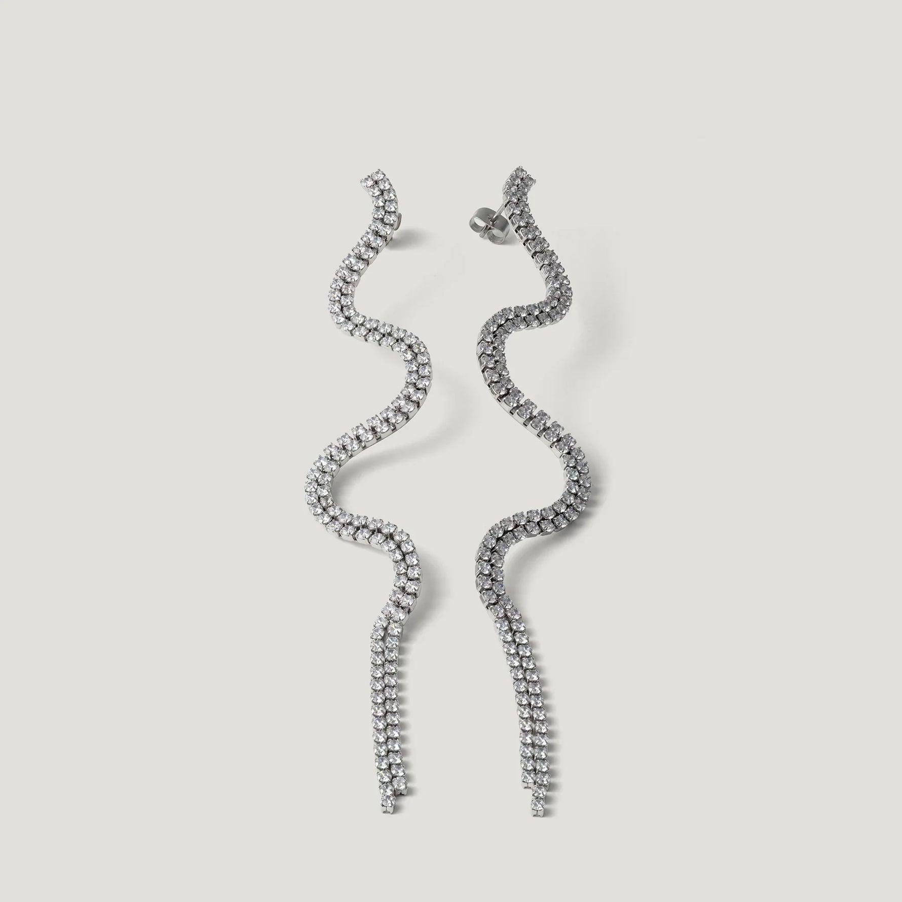 Pair of wavy silver tassel earrings with sparkling crystals on a light background
