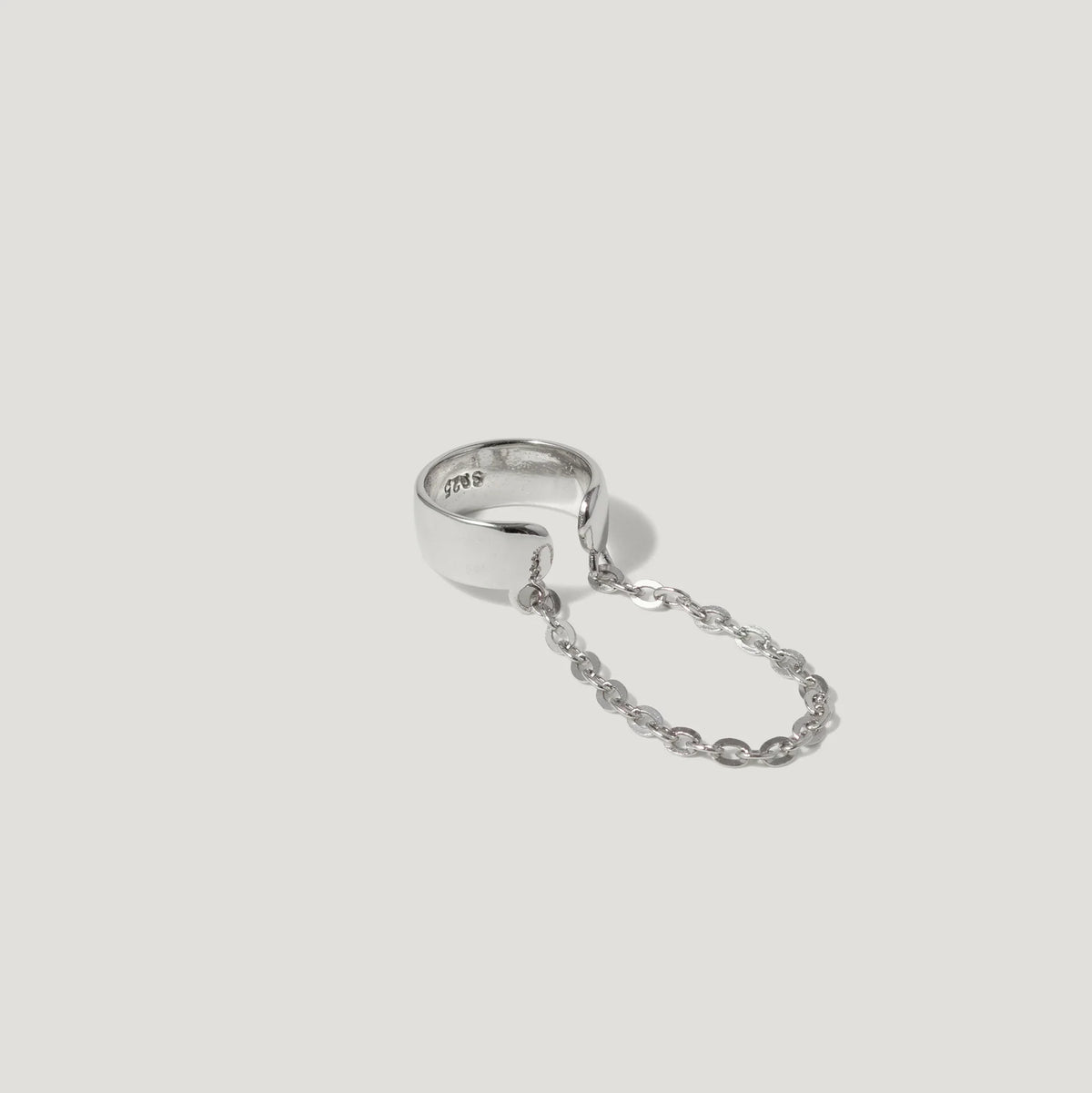Sterling silver ring with attached delicate chain on a white background