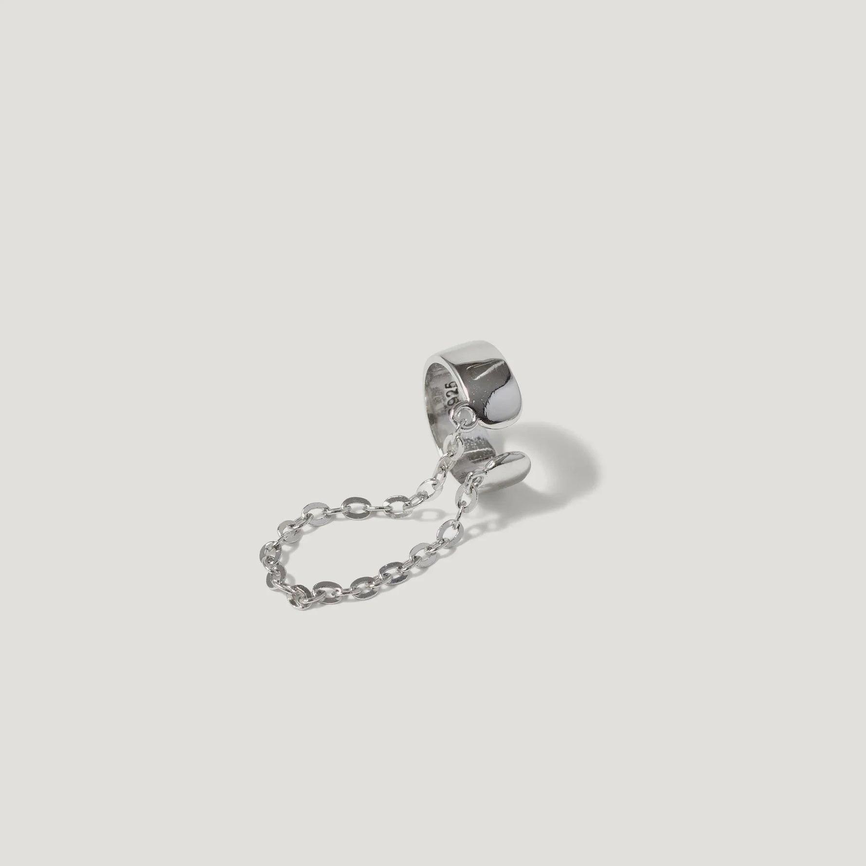 Sterling silver double ring connected by a delicate chain on white background