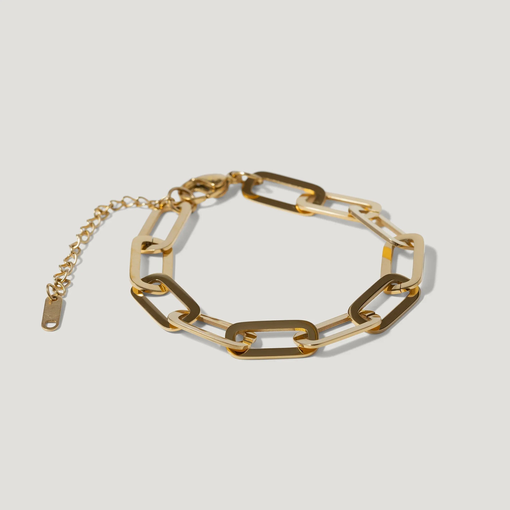Gold chain link bracelet with adjustable clasp on a white background