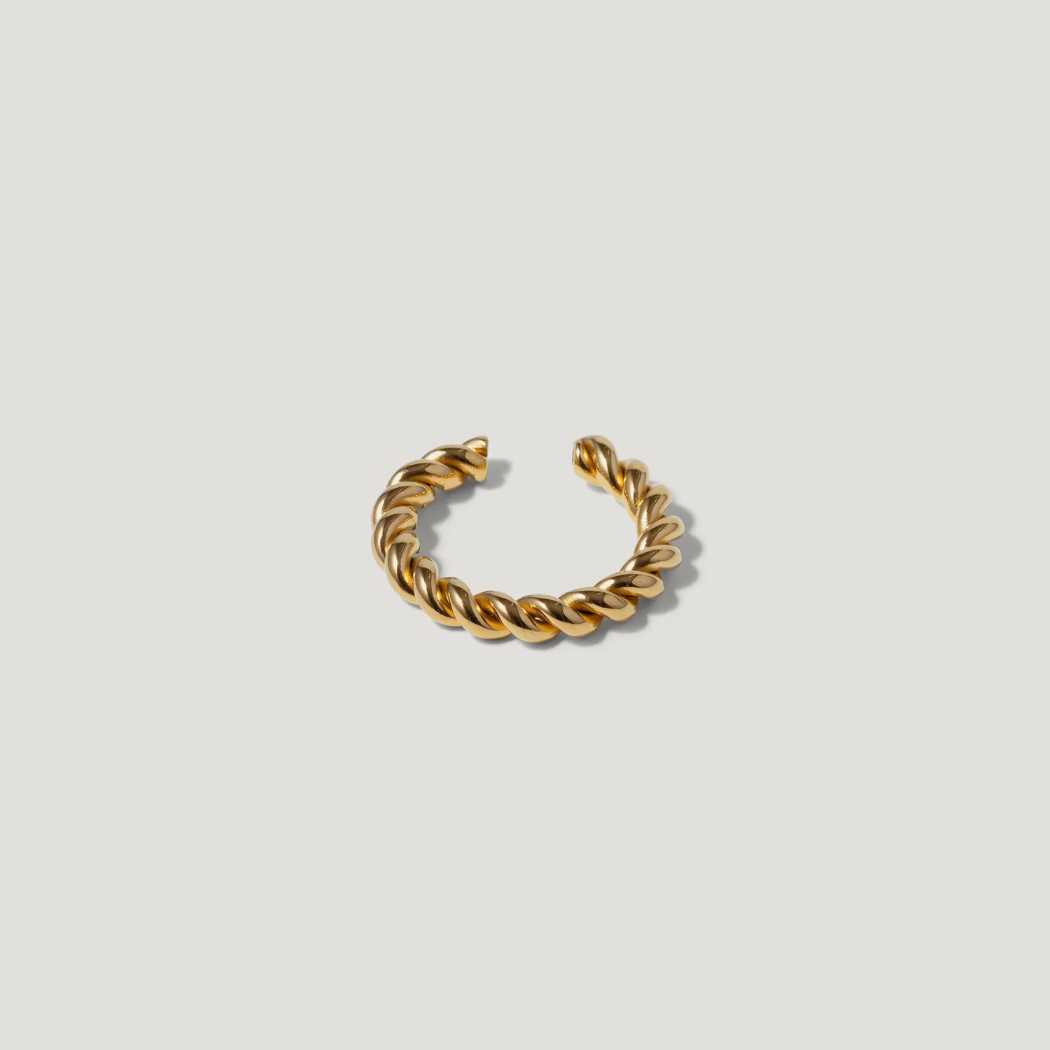 Gold twisted open cuff ring on a white background