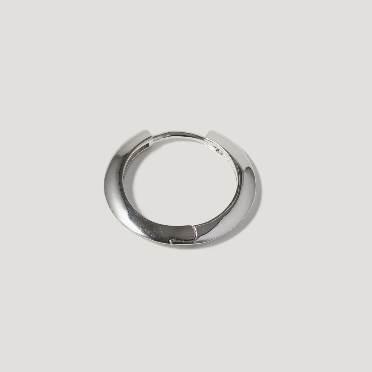 Minimalist silver hoop earring with a smooth, polished finish on a light background