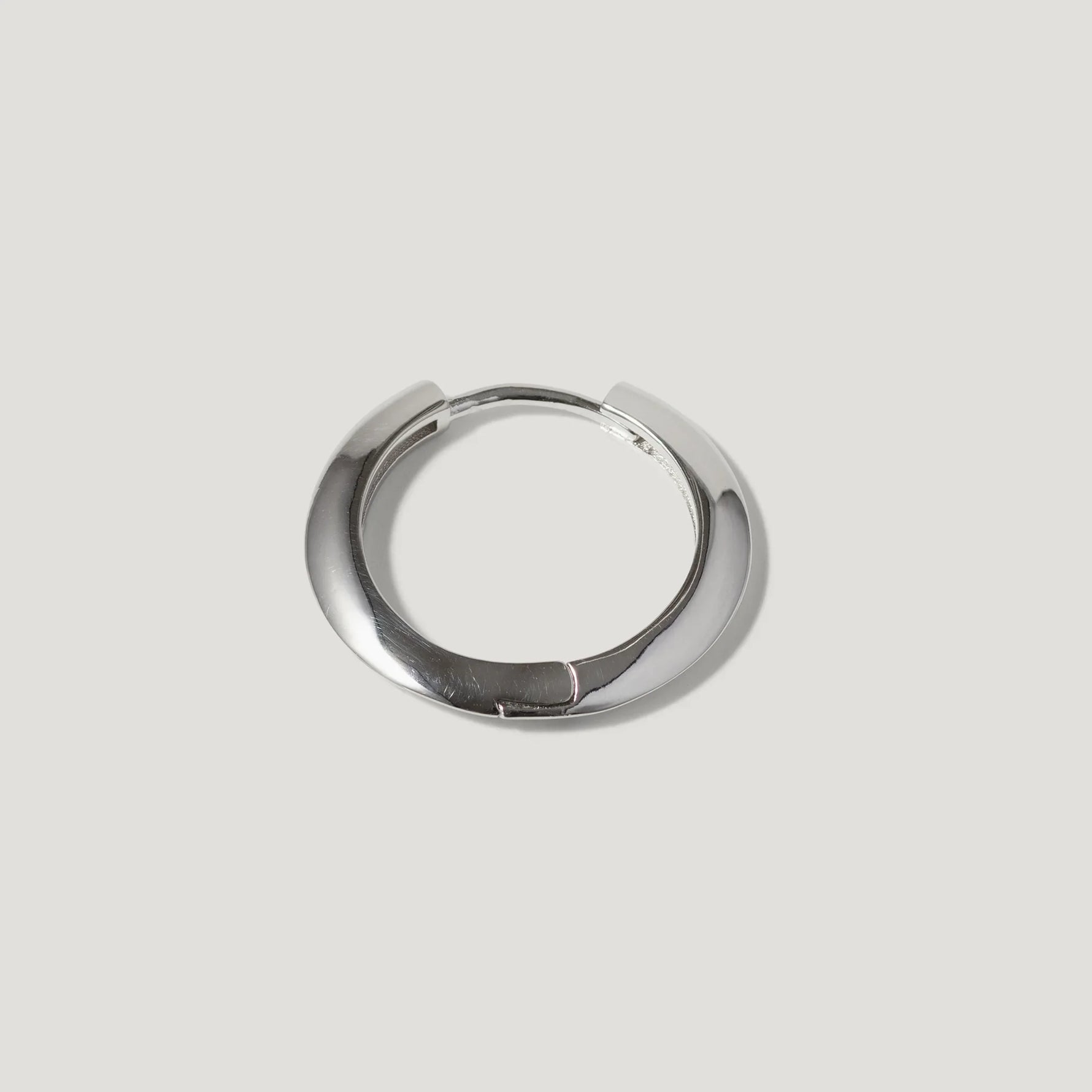 Minimalist silver hoop earring with a smooth, polished finish on a light background