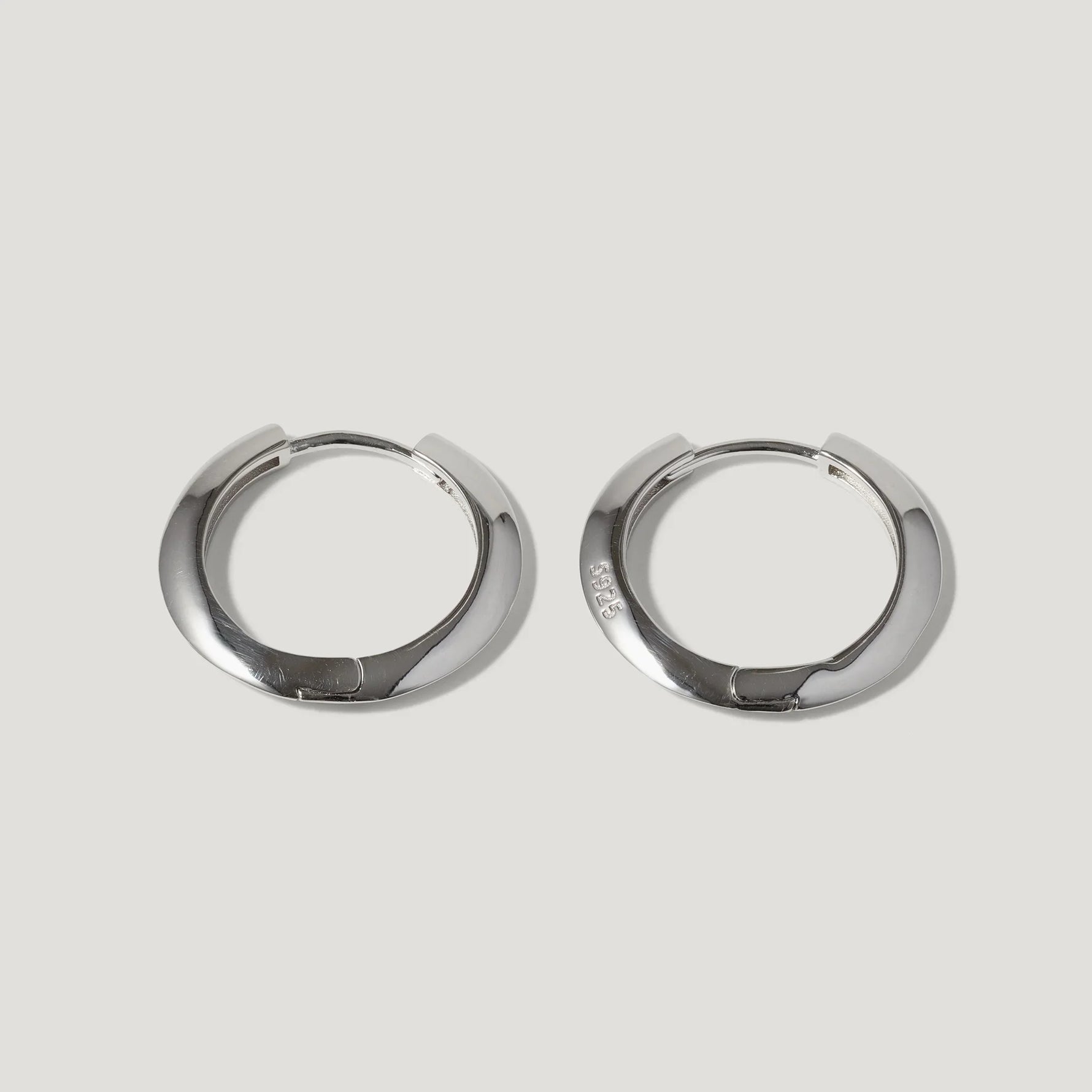 Pair of silver-tone hoop earrings with a smooth, polished finish on white background