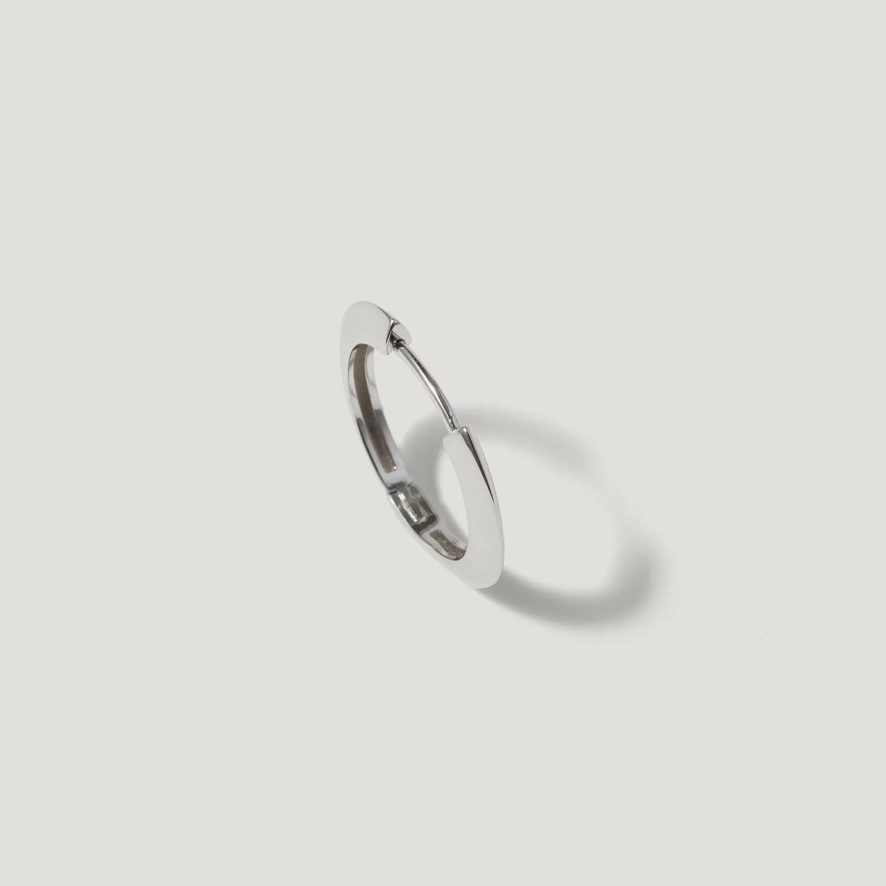 Minimalist silver hoop earring with polished finish on white background