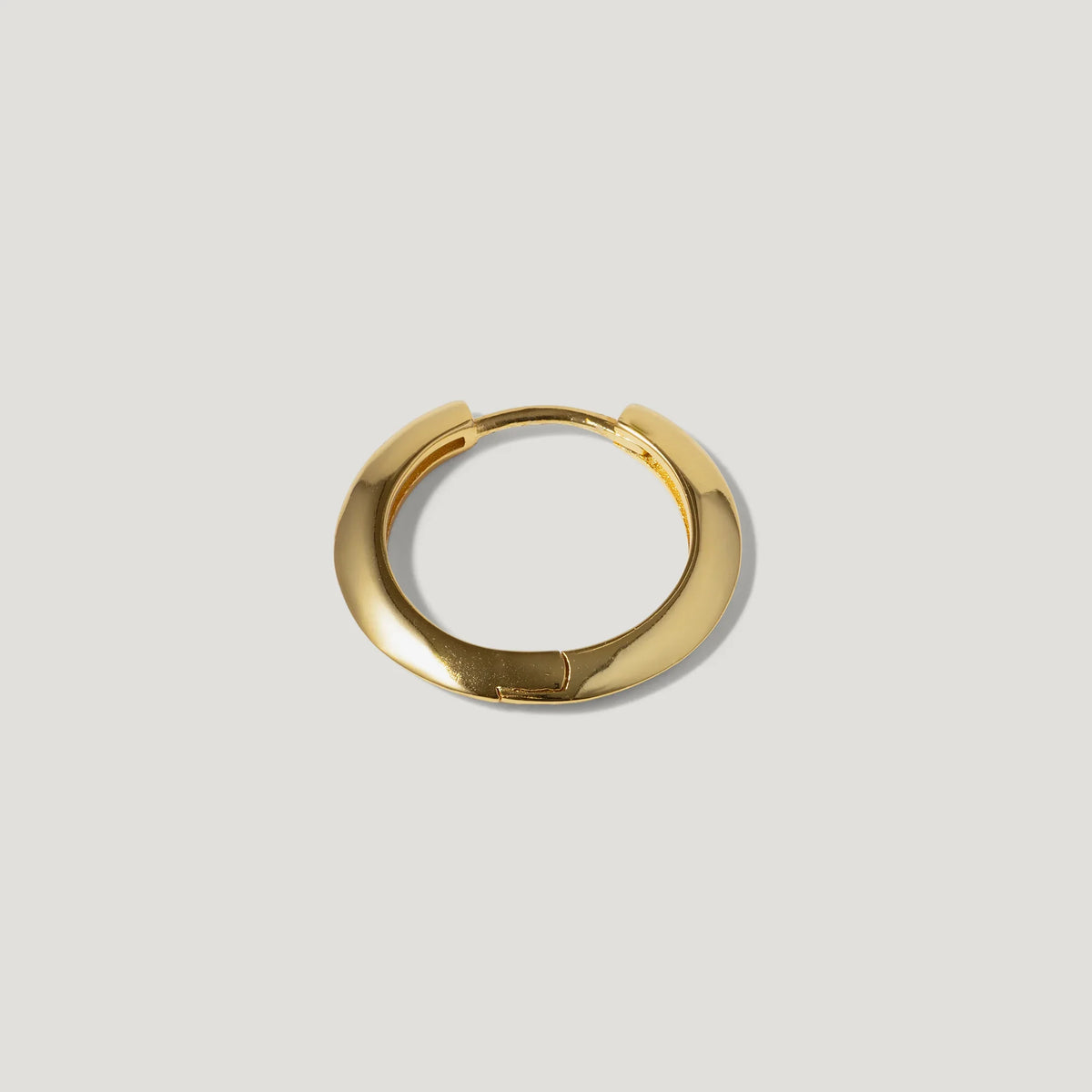 Minimalist gold hoop earring on a light background