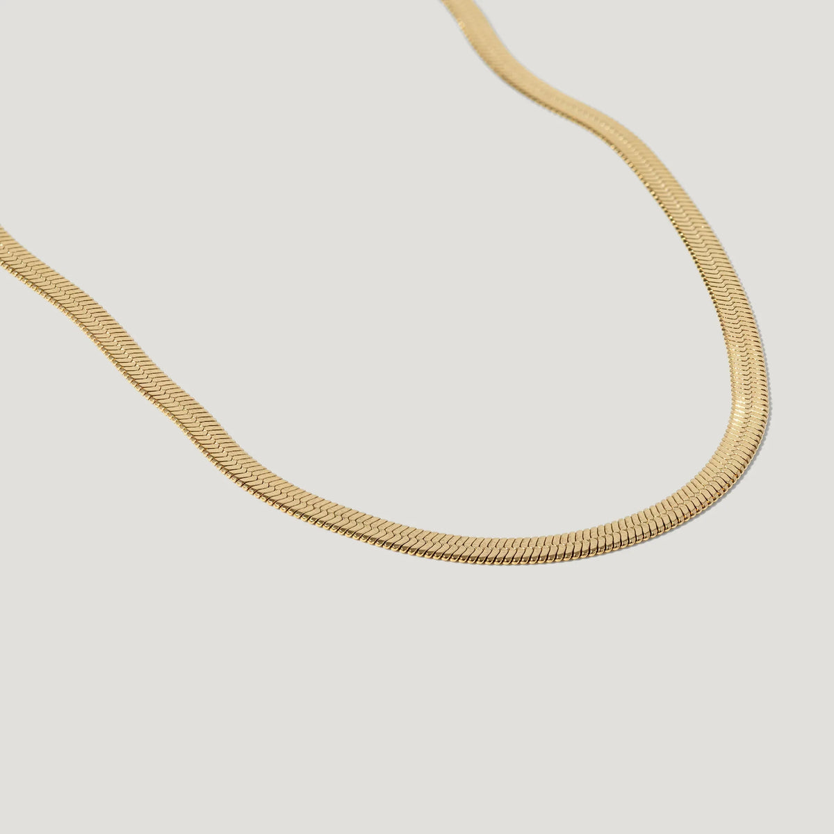 Elegant gold herringbone chain necklace on a white background