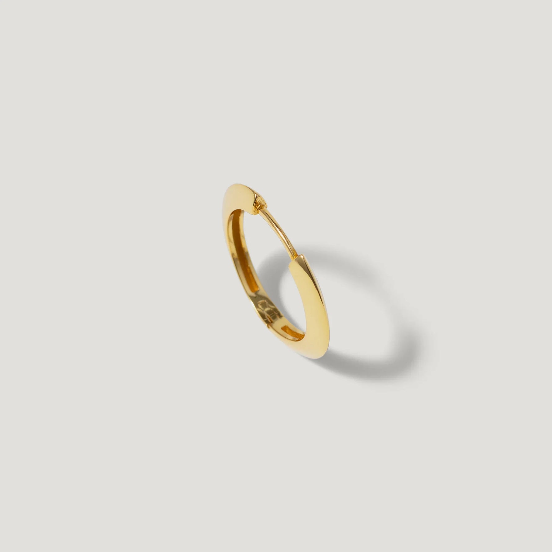 Gold hoop earring with smooth finish on white background