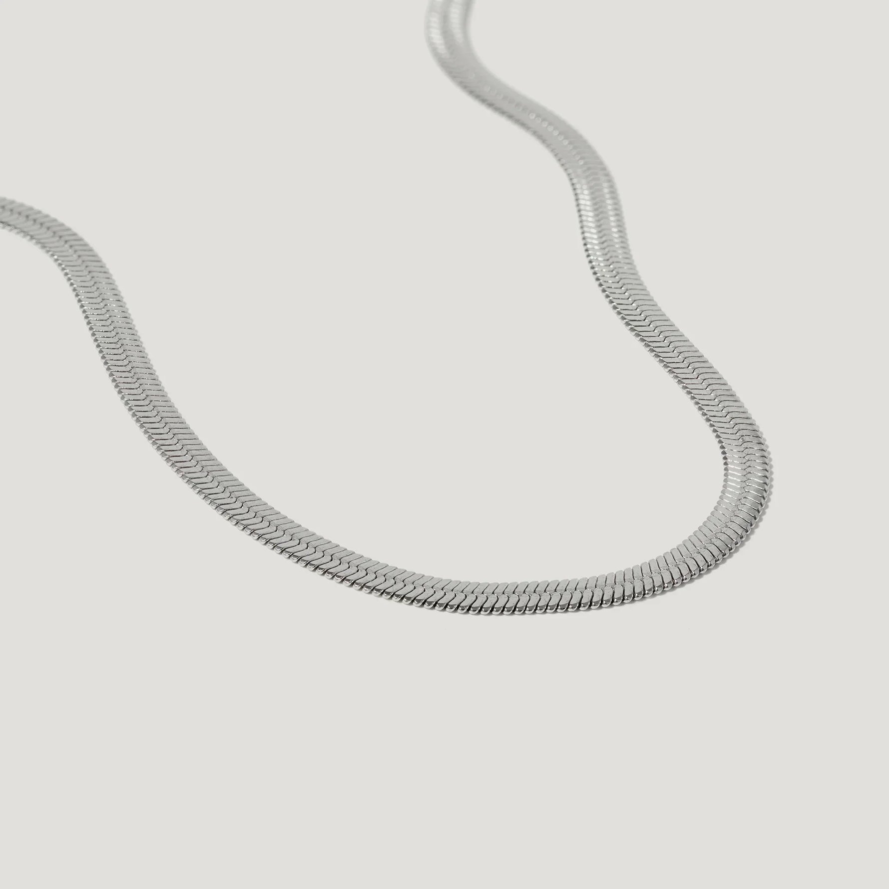 silver herringbone chain necklace on white background, minimalist jewelry