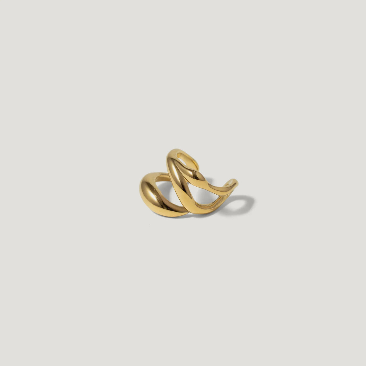 Twisted gold ring with modern sculptural design on white background