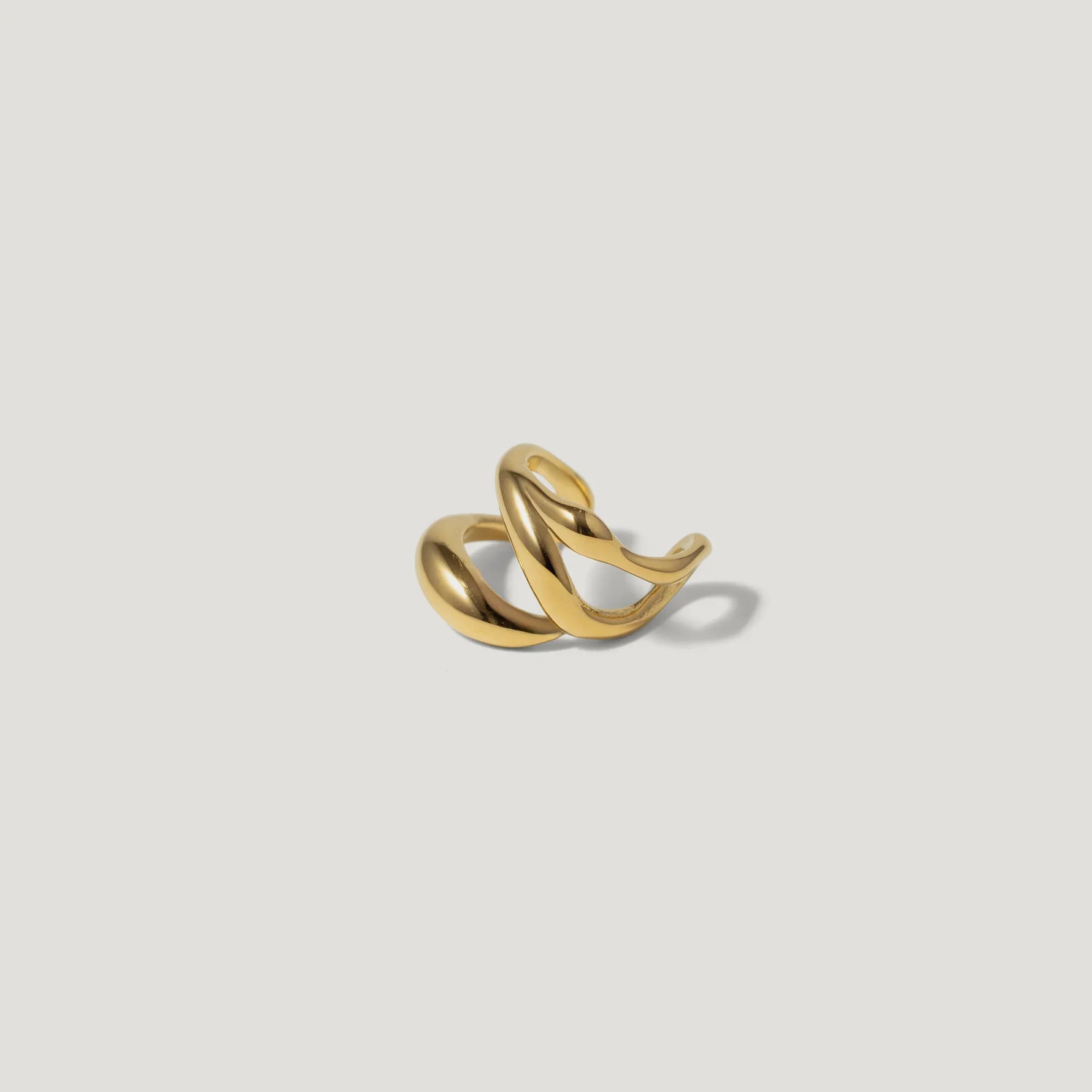 Twisted gold ring with modern sculptural design on white background