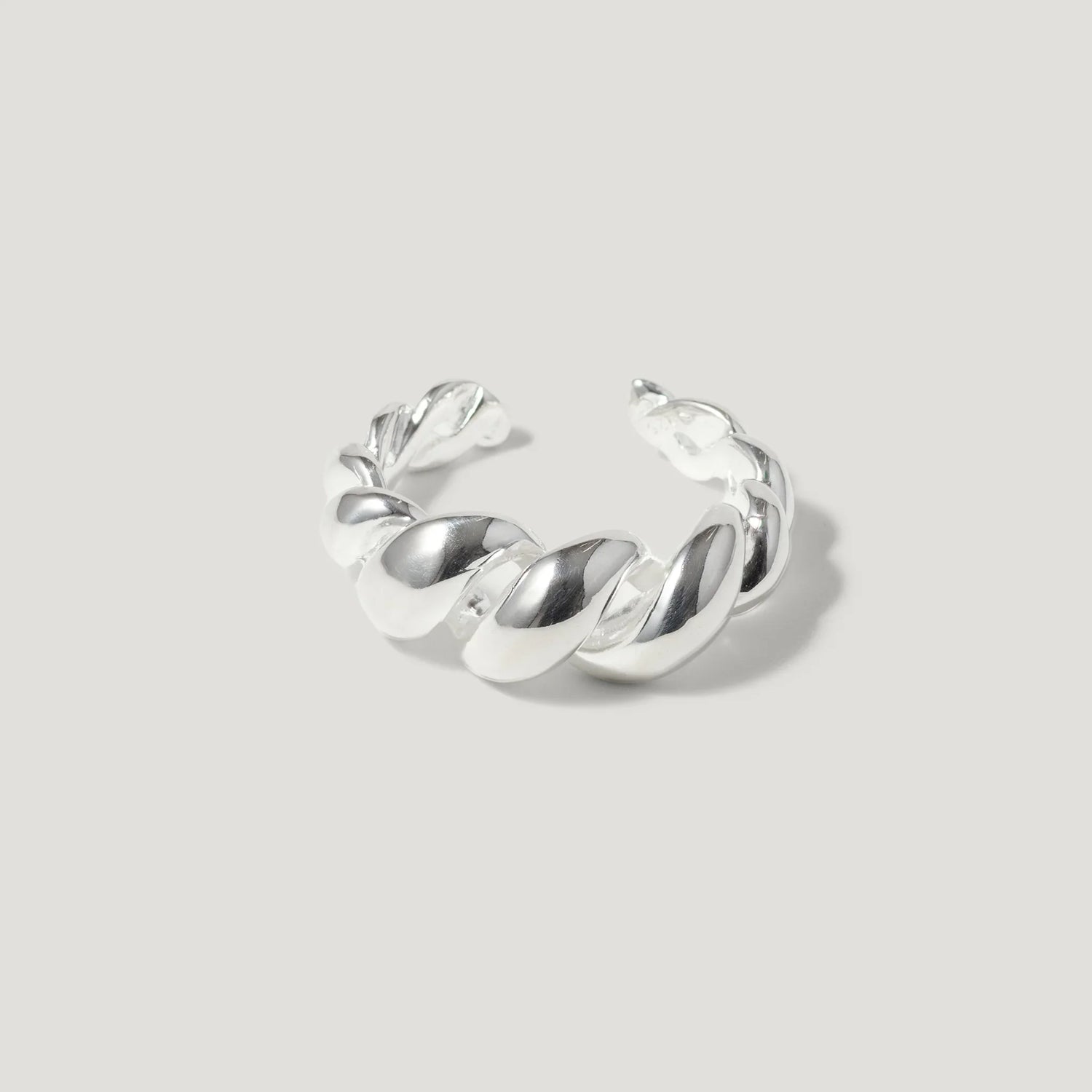 Chunky silver twisted ring with open band on light grey background