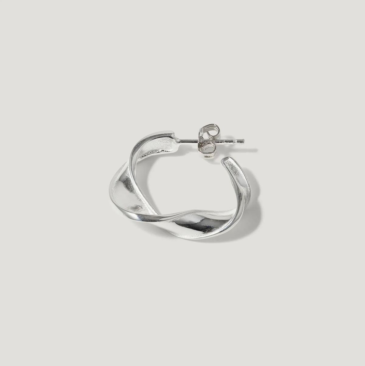 Silver twisted hoop earring with stud fastening on white background