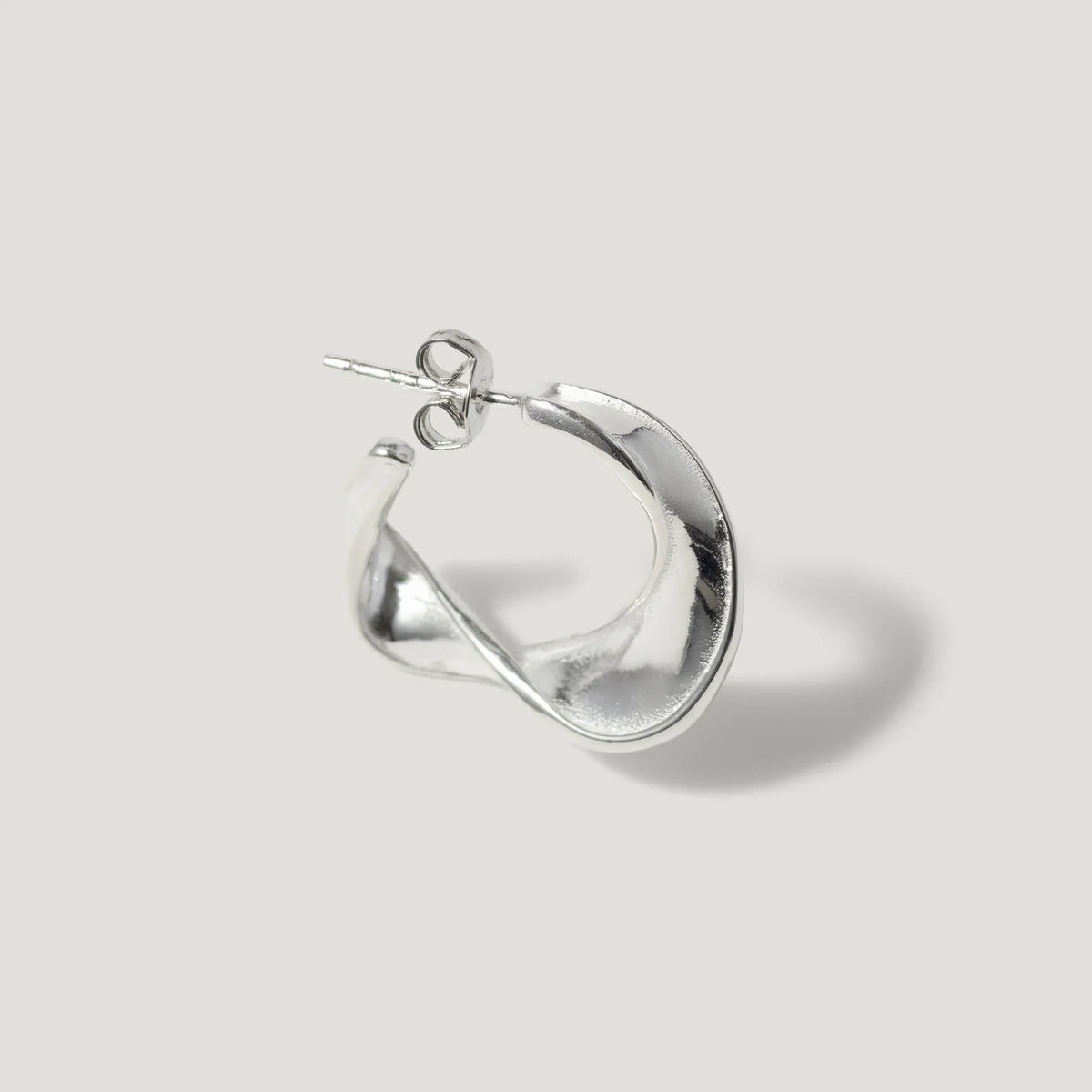 Sterling silver twisted hoop earring with a sculptural, modern design on white background
