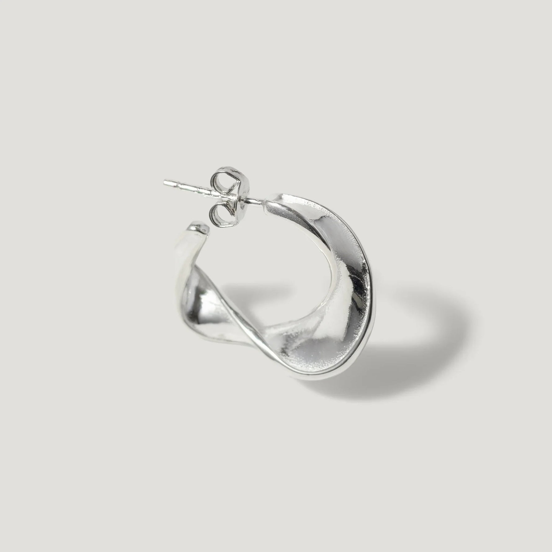 Sterling silver twisted hoop earring with a sculptural, modern design on white background