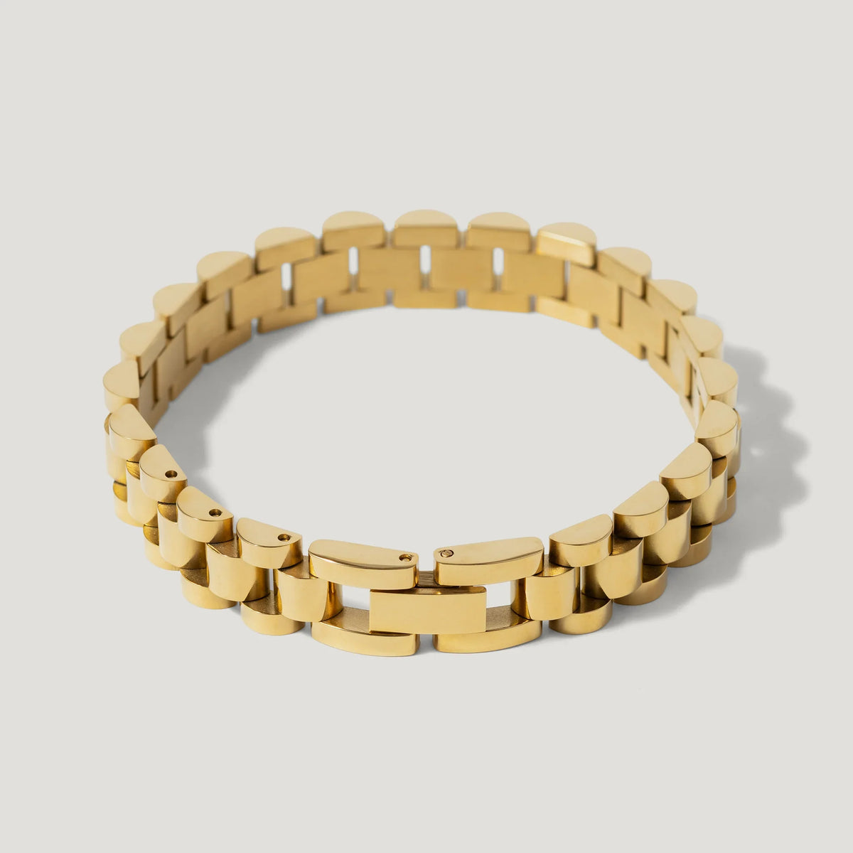 Gold link bracelet with rectangular and curved segments on a plain light background