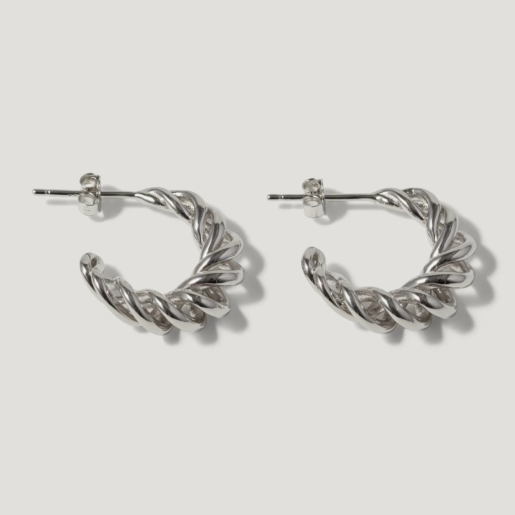 Silver twisted hoop earrings with post backs on white background